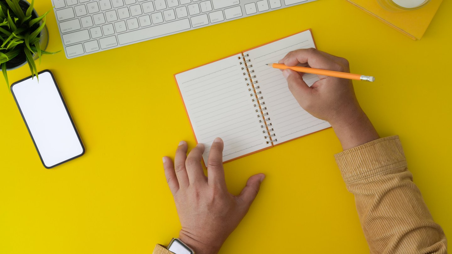 Person Writing on Notepad